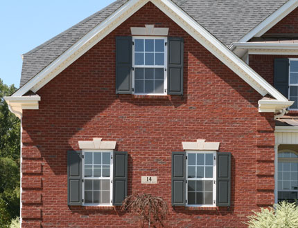 Close-up of Wooden Board and Batten Shutters on a Brick House